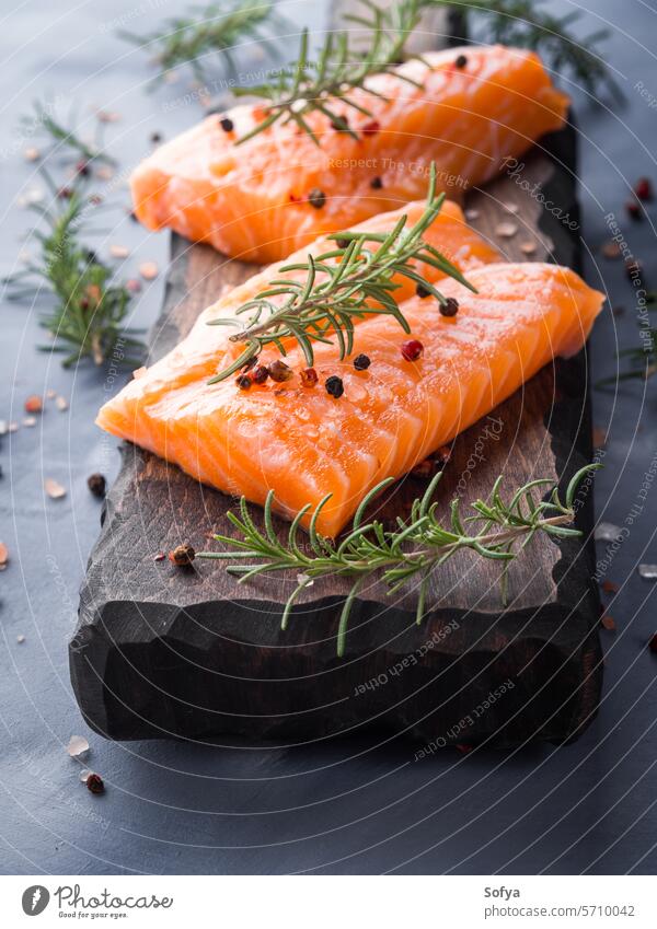 Raw salmon on wooden board with herbs fish food raw fresh seafood healthy fillet ingredient natural omega piece product rosemary slice steak closeup salt cook