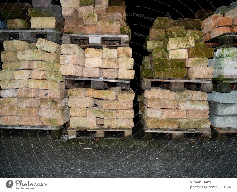 Stacked stone on pallets stones Palett building material Weathered storage weather site Logistics left behind Supply Trade frowzy mossy remnants Remaining stock
