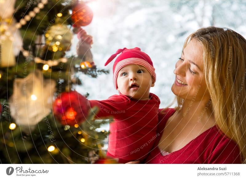 Little cute baby and his mother enjoying shiny lights and ornaments on the Christmas tree adorable beautiful care celebration cheerful child childcare childhood
