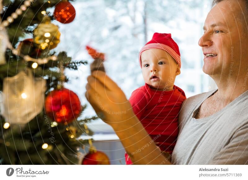 Little cute baby and his dad enjoying shiny lights and ornaments on the Christmas tree beautiful boy caucasian celebration cheerful child childhood christmas