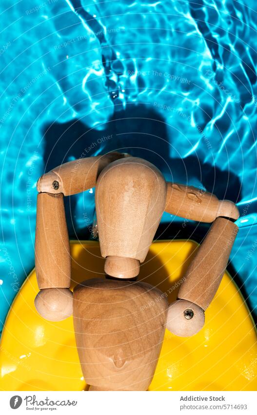 An artist's wooden mannequin lounging on a yellow float in a shimmering pool, embodying summer relaxation Pool water blue chill sunbathing model leisure
