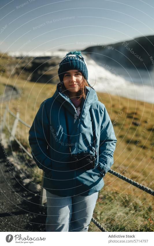 Woman tourist at Gullfoss Waterfall in sunny Iceland iceland woman female traveler gullfoss waterfall blue jacket knitted hat smile landscape nature outdoor