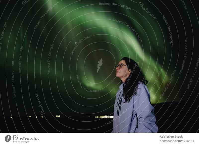 Woman marvels at Northern Lights in Iceland aurora borealis northern lights iceland woman female awe wonder night sky green glow nature astronomical phenomenon