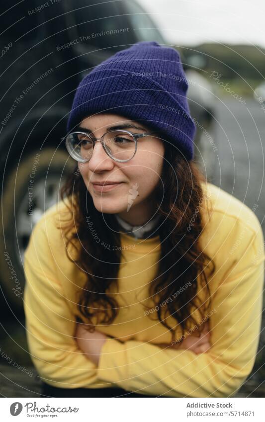 Casual Woman in a Purple Beanie Resting Outdoors woman female beanie glasses yellow sweater curly hair thoughtful resting outdoors youth fashion casual purple