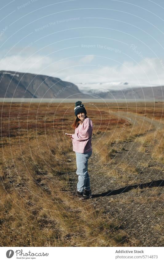 Happy woman using smartphone in scenic Iceland landscape iceland travel female nature valley technology outdoor exploration wanderlust remote connectivity
