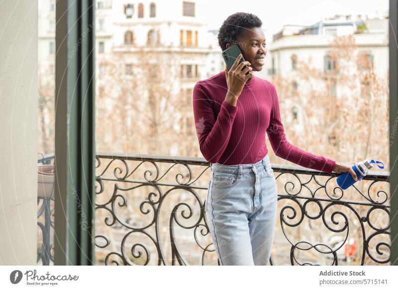 Casual conversation on a balcony with city view woman young casual attire smartphone talking urban cityscape standing railing outdoor communication technology