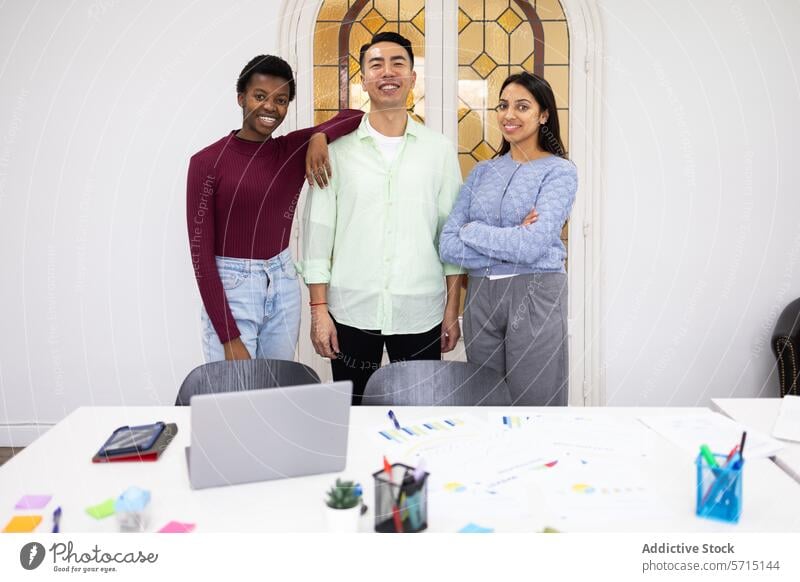 Diverse team of professionals standing in office portrait diverse multi-ethnic smiling confident modern work laptop materials table group young business