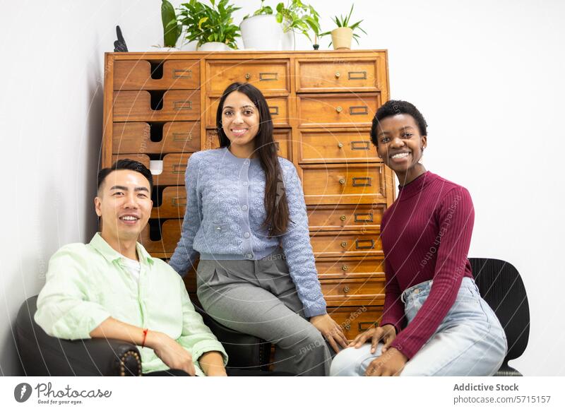 Diverse group of friends smiling in a casual setting diversity friendship smile room plant drawer cabinet furniture ethnic sitting happy joyful diverse