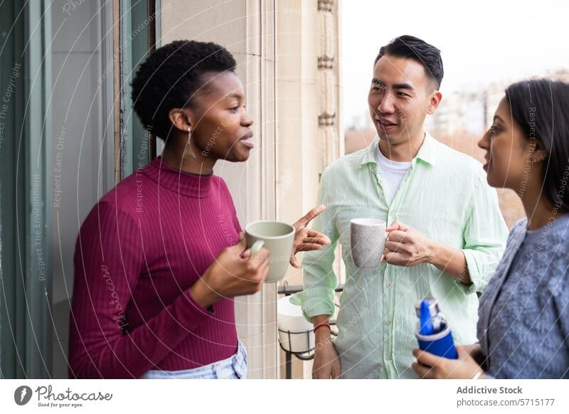 Friendly conversation among diverse friends with drinks casual balcony young adults friendly chatting multicultural socializing gathering holding coffee cups