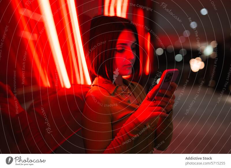 Urban evening with a woman using smartphone in red neon light urban madrid four towers business area modern lifestyle young vibrant technology city night glow