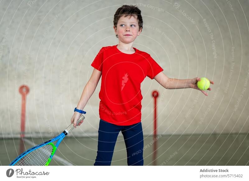 Active boy enjoying tennis sport weekend indoors racket ball active young child sportswear red t-shirt shorts navy playful health fitness hobby practice leisure