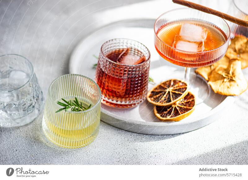 A diverse collection of spirits in ribbed glasses, including cherry liqueur with ice, limoncello with a rosemary sprig, and others, all resting tray with dried citrus decor