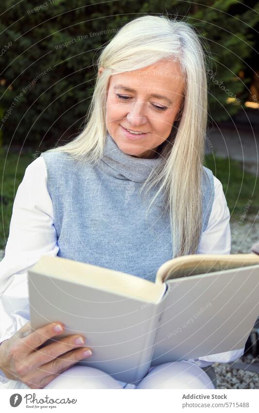 Serene woman in her 50s engrossed in reading a book, exemplifying a relaxed lifestyle moment Woman peaceful leisure mature relaxation outdoor tranquil