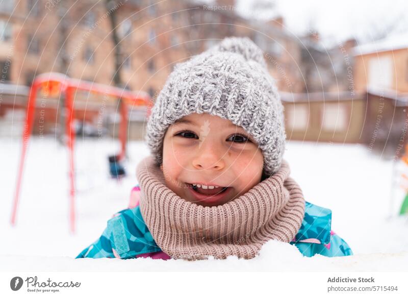 Smiling child with a woolly hat and scarf enjoying a snowy day at the playground Child smile winter outdoor cold cheerful fun season knitwear happiness chill