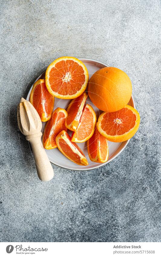 Freshly sliced oranges on a plate with a wooden juicer citrus fruit fresh whole ceramic gray surface textured food healthy vitamin juicy ripe manual tool