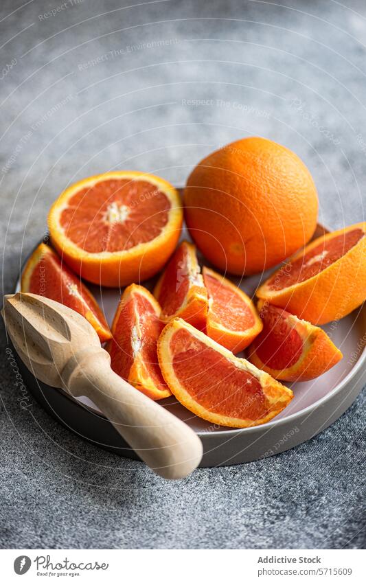 Freshly sliced oranges on a plate with a wooden juicer fruit citrus ripe fresh grey background textured food healthy vitamin c juicy segment pulp natural snack