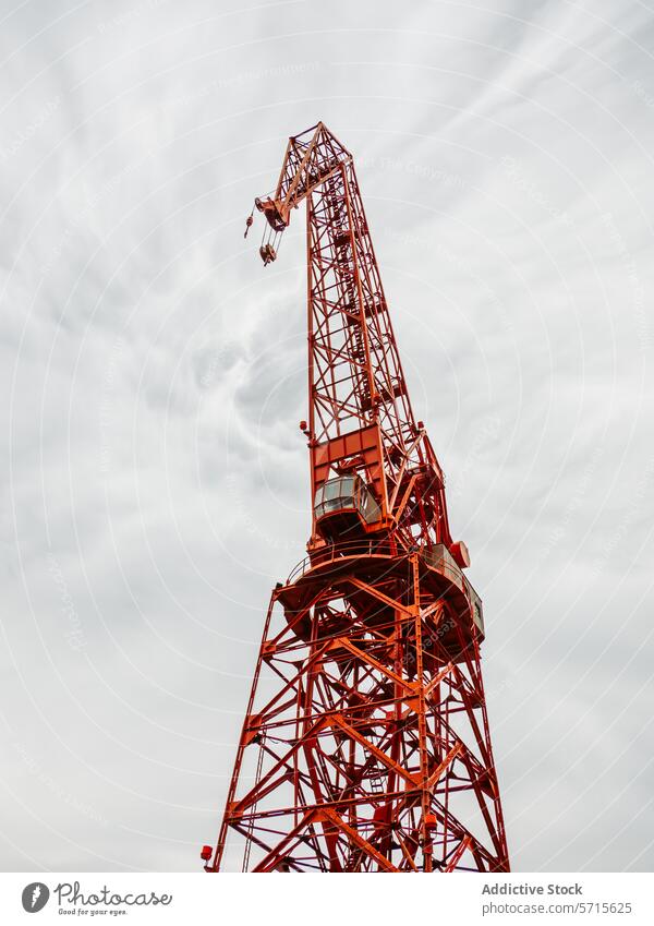 Red construction crane against a cloudy sky backdrop red industrial structure building development towering machinery equipment engineering project high metal