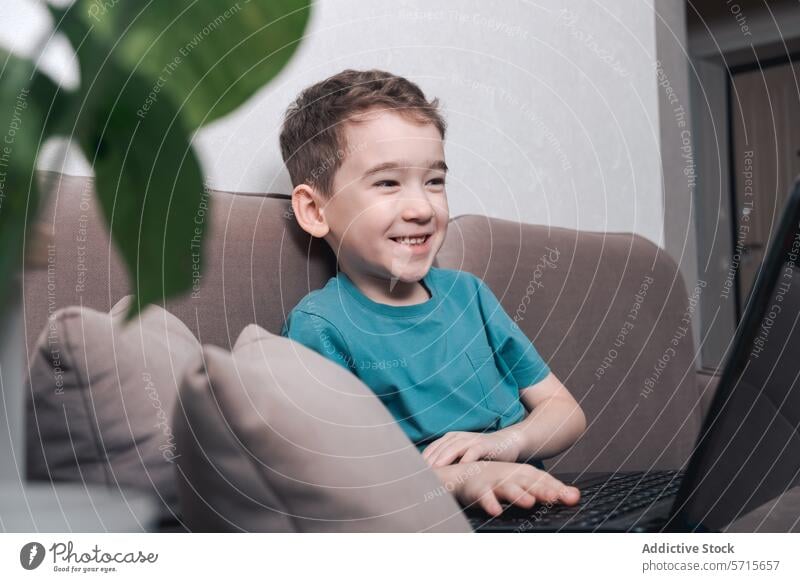 Child smiling while engaging with modern technology child laptop home interaction boy computer digital learning online education entertainment casual indoor