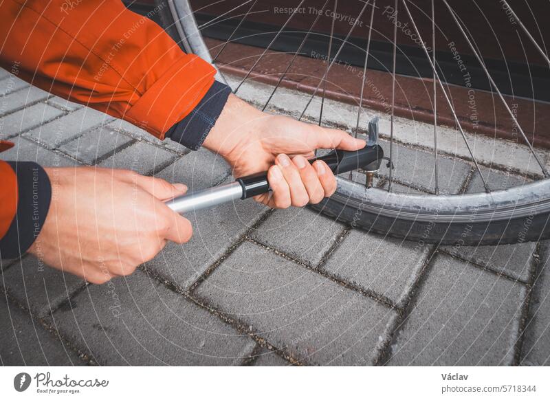 Man prepares his road bike for the season. Blowing out the bike's inner tube with a hand bicycle pump. Outdoor sport. Regular maintenance service wheel pressure