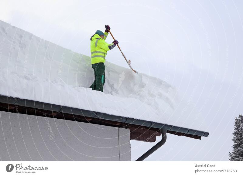 A man clears heavy snow from the roof of a house snowplough men Snow Winter snow shovels Roof House (Residential Structure) house roof snow-laden Weight peril