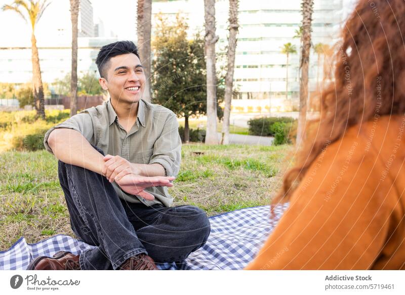 Students sharing a conversation on a sunny picnic student park smiling man woman multiethnic young urban casual outdoor leisure friendship diversity daytime