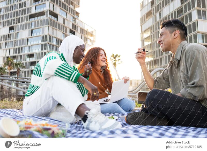 Multiethnic students sharing a meal and studying outdoors picnic laptop food diversity multiethnic african american woman urban city friendship education