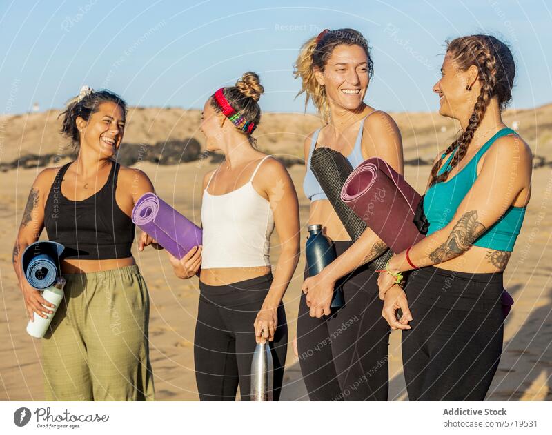 Friends smiling and holding yoga mats on the beach women friends laughing carrying group happy class exercise fitness health well-being relaxation leisure
