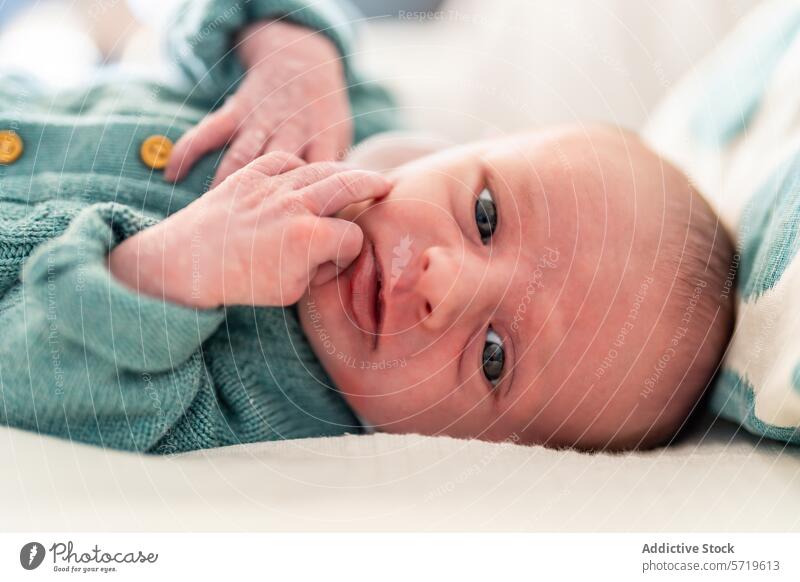 A close-up of a newborn baby with a contemplative expression, lying comfortably and gazing at the world around thoughtful gaze comfortable infant child life