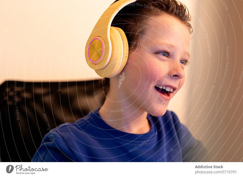 A delighted young boy wearing headphones laughs while looking at a computer screen, suggesting a positive online interaction or discovery child happiness