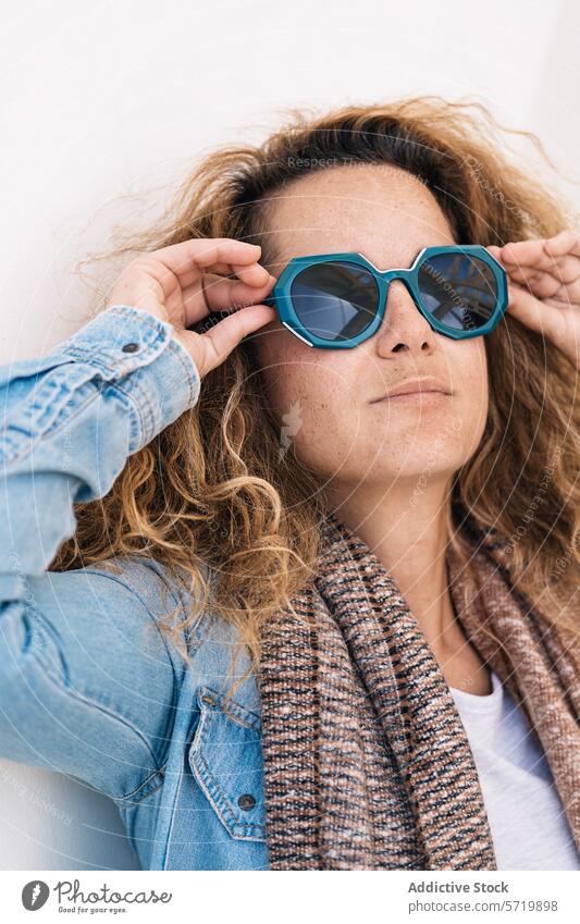 A confident woman with an adaptive hand grip stylishly adjusts oversized sunglasses, embodying resilience and fashion-forward thinking individual female lady