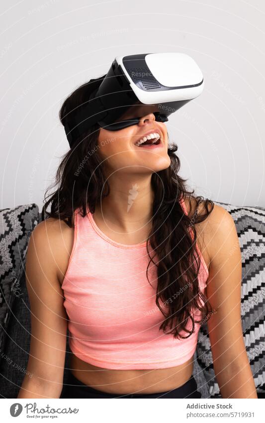 Smiling young woman experiencing virtual reality adult vr headset hispanic middle eastern female 20s smile amusement joy pink top sleeveless brown hair