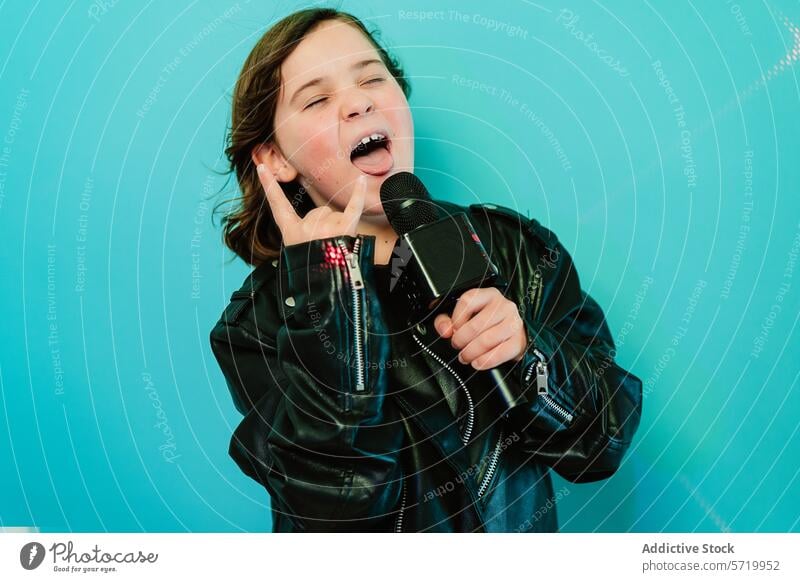 A spirited young girl with a rockstar attitude sings into a microphone, flashing a rock sign, against a light blue backdrop kid singing music party
