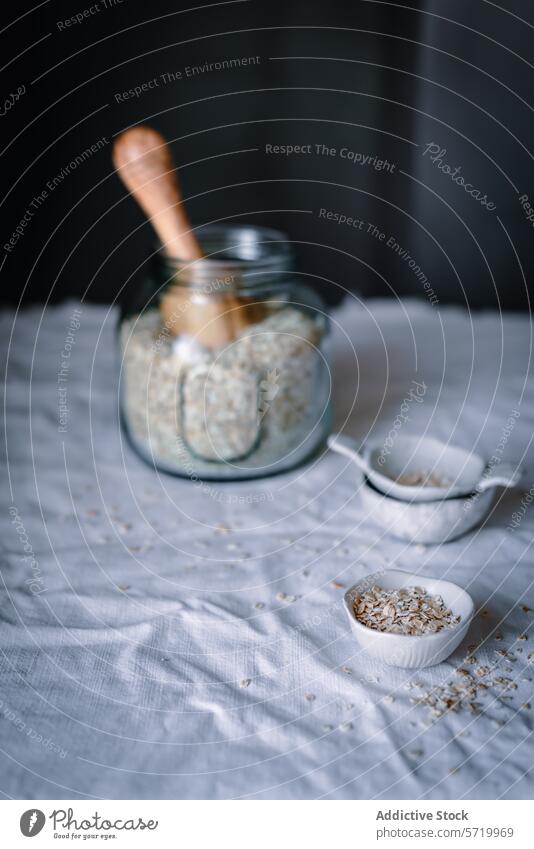 Artisanal oat milling setup on kitchen table homemade jar wooden scoop linen cloth bowl flake glass clear artisanal food preparation healthy lifestyle