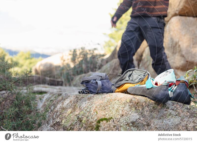 Close-up of essential climbing gear placed on a rocky surface with blurred anonymous climbers in the background, ready for a mountain adventure equipment