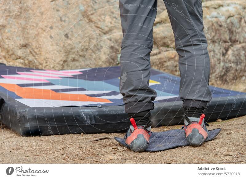 Anonymous climber stands on a crash pad, ready to tackle the boulder, showcasing the specialized climbing shoes feet bouldering close-up gear outdoor