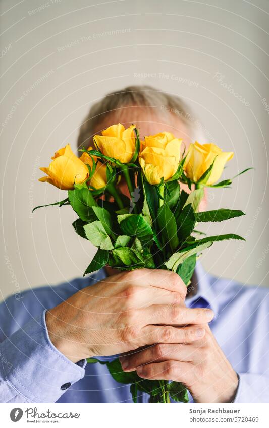 A man holds a bouquet of yellow roses in front of his face. Man Bouquet Yellow hands stop Gift Spring valentine romantic Flower Love Plant Nature Blossom date