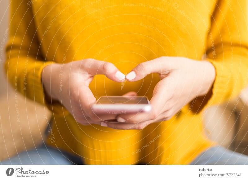 Close-up of hands texting on a smartphone. heart shape yellow sweater communication digital connectivity affection close-up technology mobile phone social media