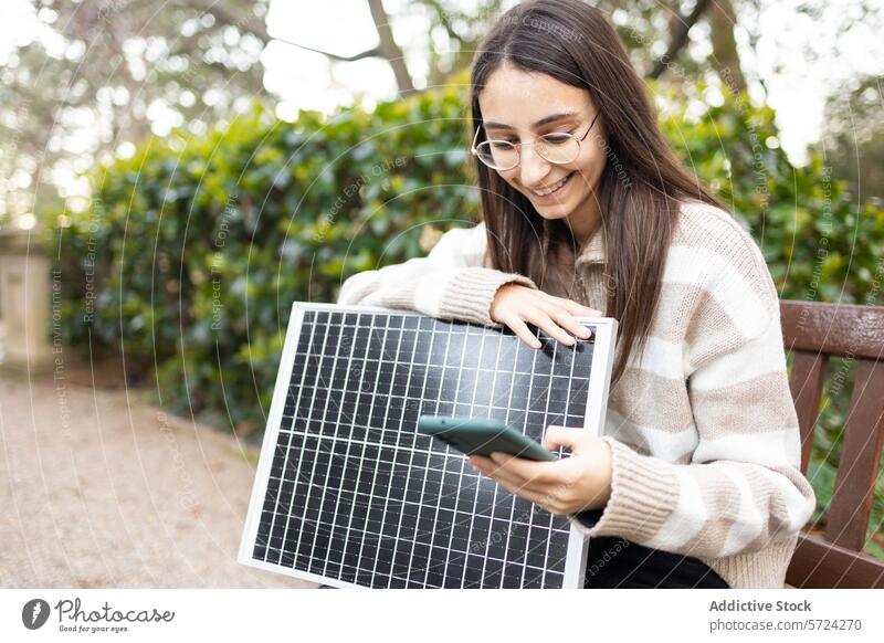 Young woman learning about solar panels in a park smartphone bench renewable energy education smiling outdoors young adult technology study environmental