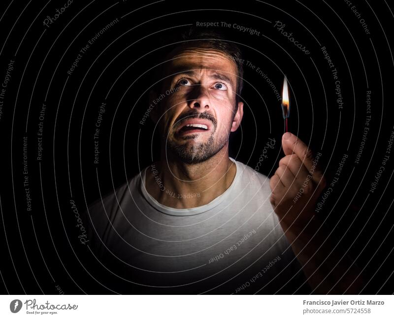 Worried man with a match in the dark. Blackout concept. darkness face blackout electricity flame hand light worried night confused stressed copy space fire