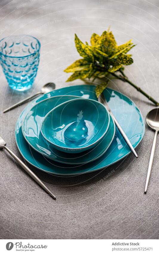 Elegant turquoise tableware set on gray background from above setting bright ceramic dinner dishware cutlery textured surface decorative plant nature elegant