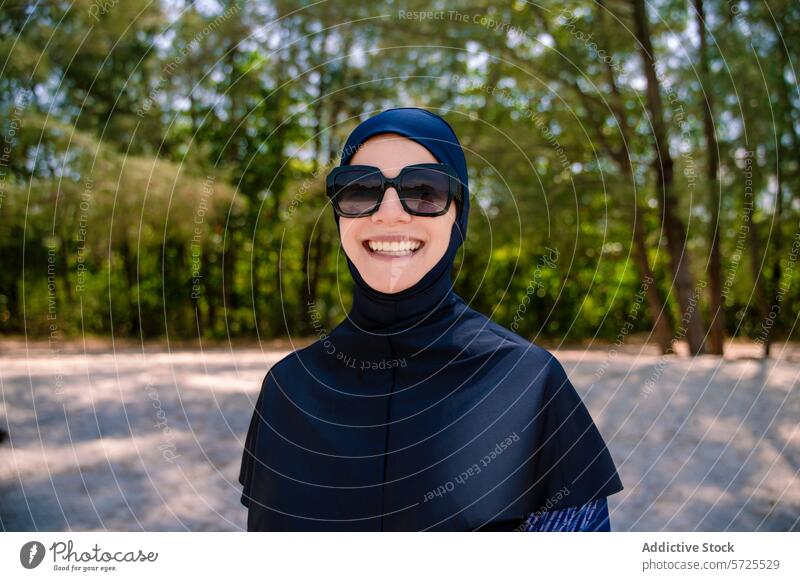 Smiling woman in burkini enjoying sunny beach day muslim modest swimwear smile happy nature outdoors hijab modesty comfort fashion sand sunny day eyewear