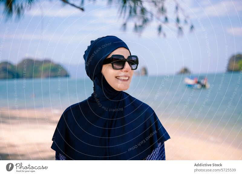 Smiling woman in burkini enjoying the beachside view smile sea sunglasses modest swimwear muslim fashion sand sunny island shore coastline headscarf comfort