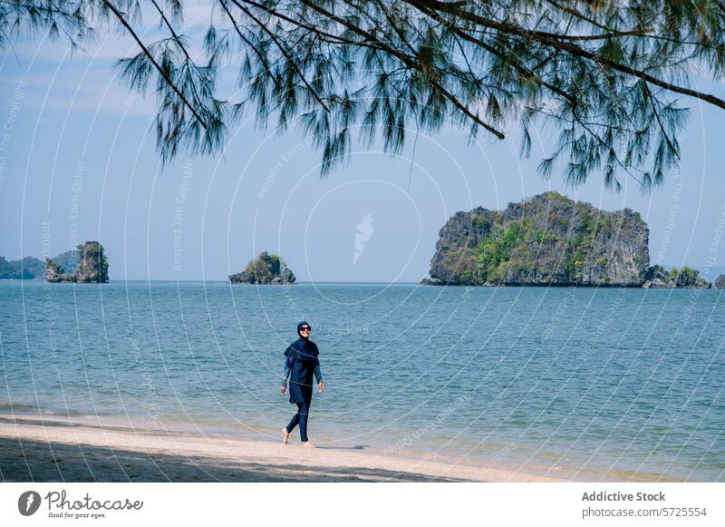 Muslim woman in burkini enjoying a beach day muslim sea island swimwear modest shade tree stroll walking coastline tropical summer vacation holiday leisure
