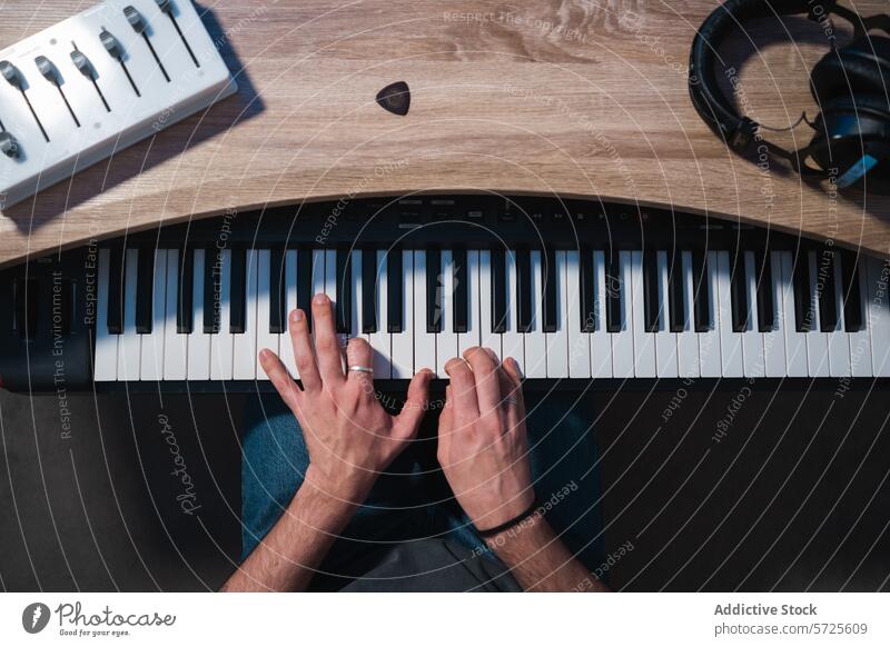 Top view of hands playing electronic keyboard in studio musician sound session production recording equipment mixer headphones synthesizer artist creativity
