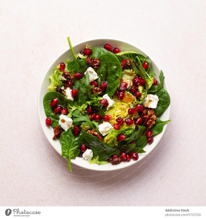 A vibrant winter salad featuring candied walnuts, juicy pomegranate seeds, mixed greens, creamy goat cheese, cranberries, and a rich fig jam vinaigrette