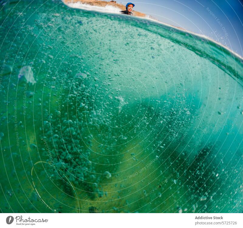 The perspective of a surfer surrounded by the intense turquoise hues and effervescent textures of a wave's barrel, under a clear sky ocean sea water bubble