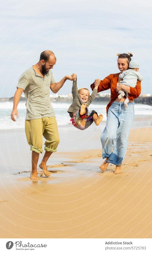Joyful family moment on a sandy beach fun playful joy happiness sunny day adults child swinging arms outdoor leisure activity casual clothing togetherness