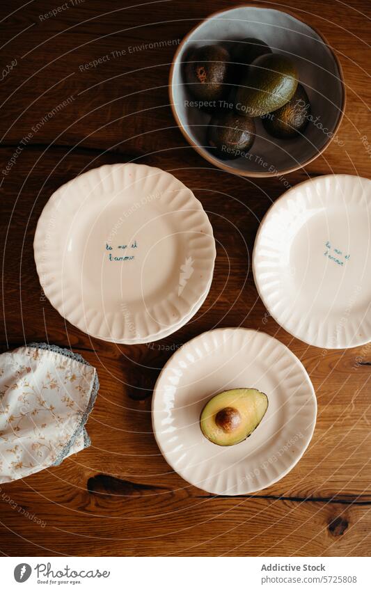 Avocado halves and whole avocados in a kitchen setting ripe bowl plate wooden surface top-down view artistic halved fruit handwritten phrases food healthy