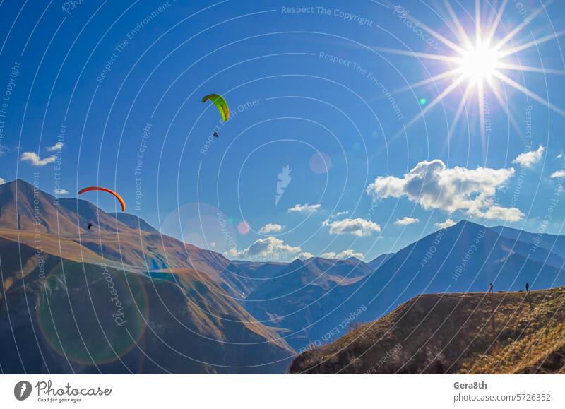 paragliders and tourists in mountains of the Caucasus with sun flare bright europe extremal extreme extreme sport fly flying gorge journey landscape
