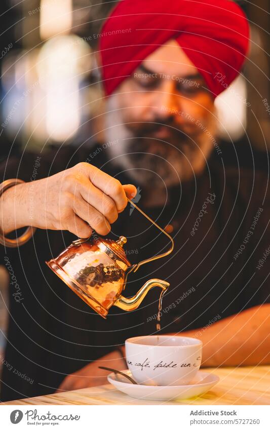 Man with red turban pouring tea into a cup man copper teapot white wooden table beverage drink tradition culture serve hospitality cafe focus selective blur